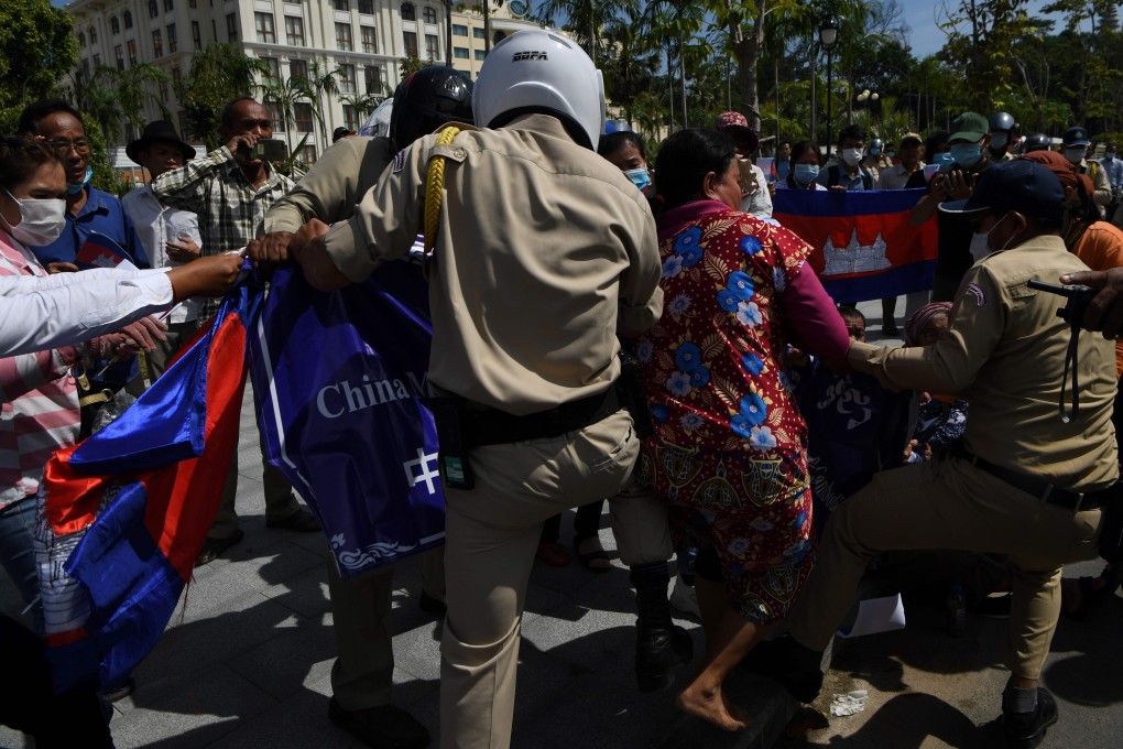 A guard confiscates a banner from protesters in Phnom Penh instructing China to respect Cambodia’s constitution. Photo: AFP