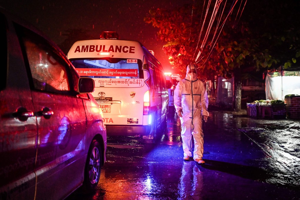A volunteer wearing personal protective equipment alongside an ambulance as Yangon residents are transferred to a quarantine centre. Photo: AFP