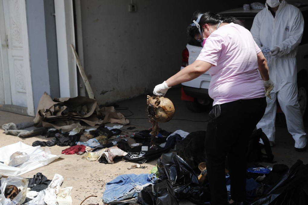 A forensic worker holds a skull as she collects human remains from a container sitting in Asuncion, Paraguay on Friday. Photo: AP Photo