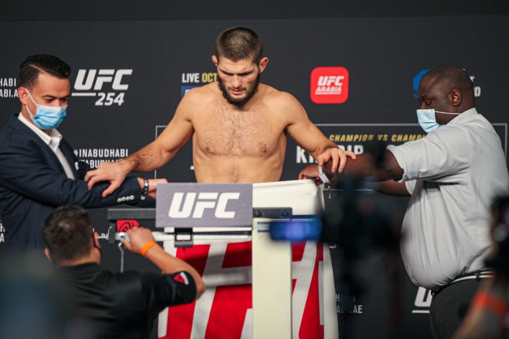 Officials hold a towel up to cover Khabib Nurmagomedov's naked body at the UFC 254 weigh-ins as another checks the scale. Photos: Amy Kaplan
