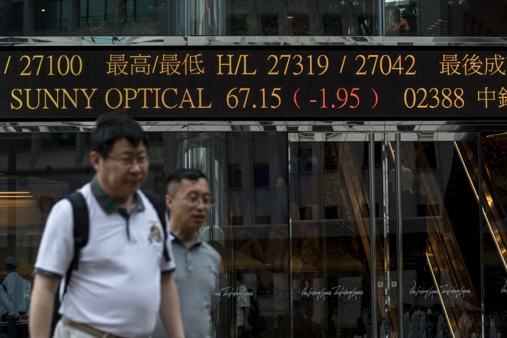 People walking past a electronic board showing the Hong Kong stock prices near the Hong Kong Stock Exchange building in Central. Photo: Warton Li