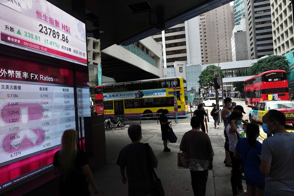People walking past a bank's electronic board showing stock index and prices near the Exchange Square in Central, Hong Kong. Photo: AP
