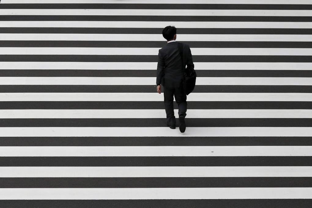 A businessman crosses a road in Tokyo’s business district in October 2015. Since the early 1990s, Japan has battled deflation. Photo: Reuters