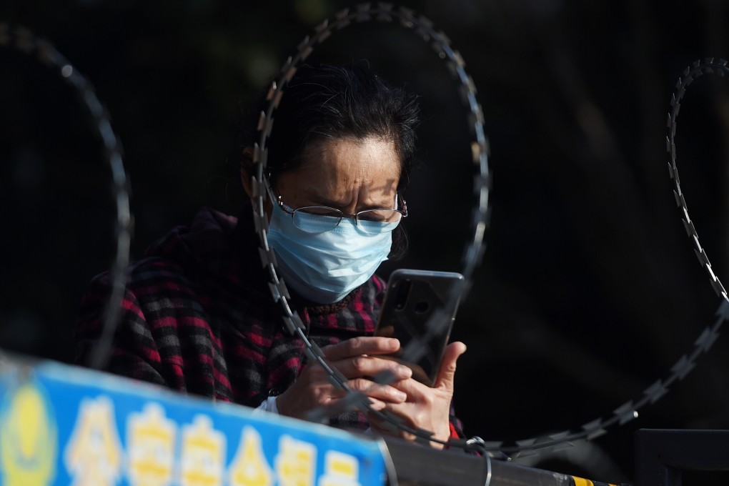 A woman uses her mobile phone in February behind barbed wire at the entrance of a residential compound in Wuhan, the epicentre of the novel coronavirus outbreak. Photo: Reuters