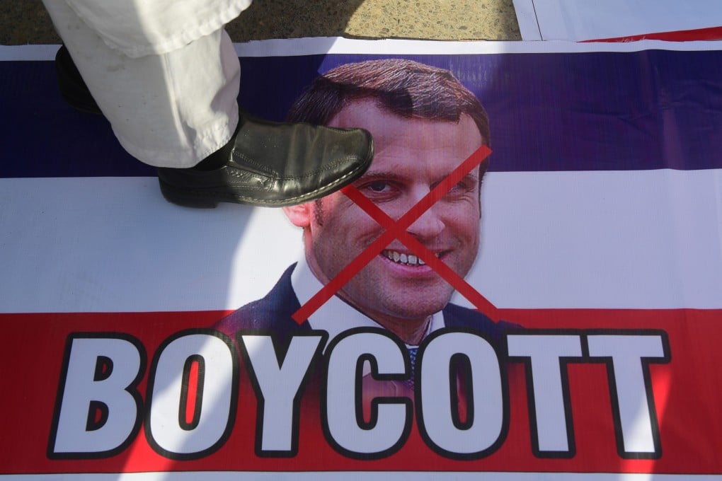 A protester stands over a picture of French President Emmanuel Macron in Karachi, Pakistan on Tuesday. Photo: AFP