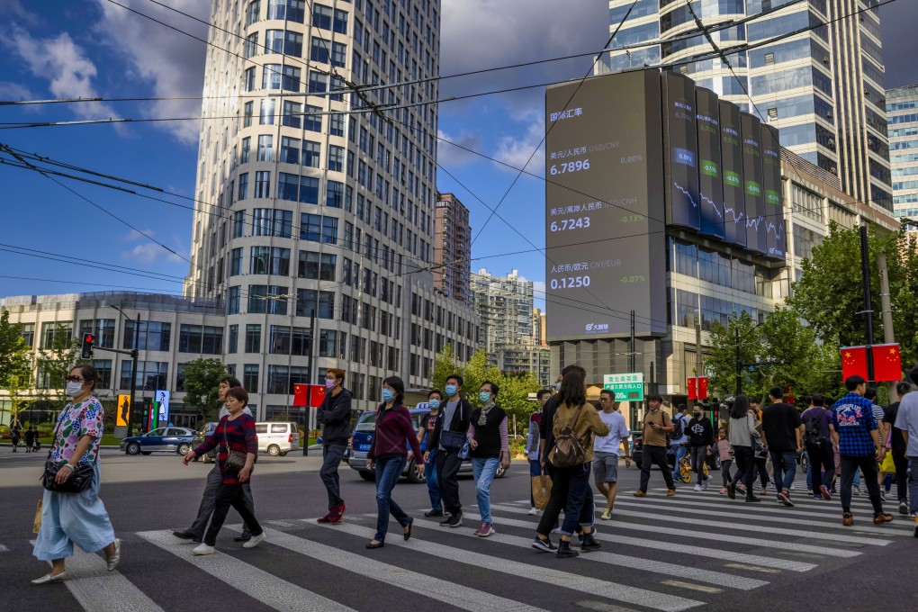 People cross the street beneath a jumbo screen showing the latest stock and currency exchange data in Shanghai on October 8, 2020. Photo: EPA-EFE