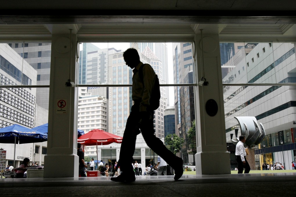 An office worker silhouetted against the skyline of Singapore’s financial hub. Photo: AP