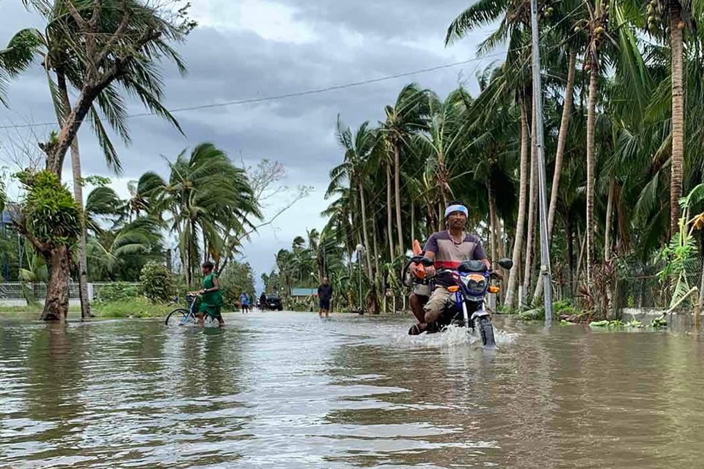 A motorcyclist traverses a flooded street in Pola, Oriental Mindoro province, on October 26, 2020. Photo: AFP