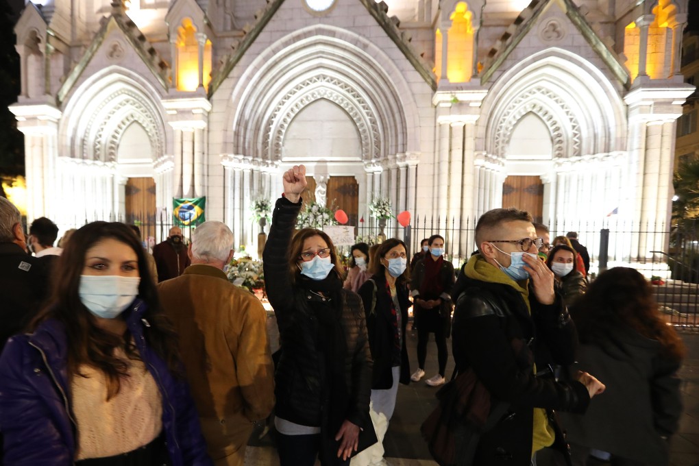 A woman raises her fist outside Notre-Dame de l'Assomption Basilica in Nice on Saturday, to pay tribute to the three victims of a knife attacker. Photo: AFP