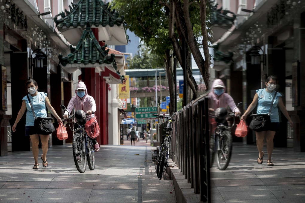 Two women are reflected in a glass panel at the Chinatown district of Singapore. Photo: EPA