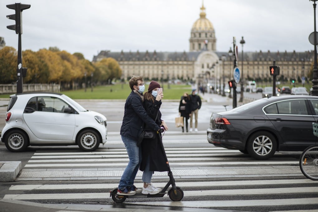 A masked couple ride an electric scooter past the Invalides memorial in Paris on October 25. A curfew intended to curb the growing spread of the coronavirus has been imposed in many regions of France including Paris and its suburbs. Photo: AP