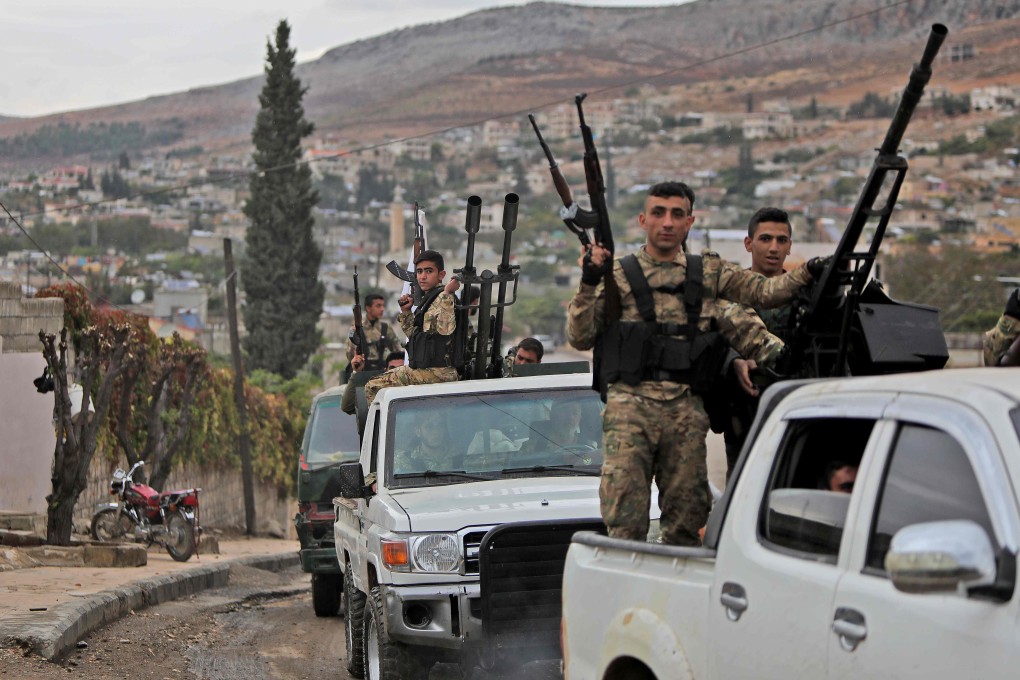 Syrian fighters from the Turkish-backed Hamza faction drive through the village of Bassouta, south of the city of Afrin on Tuesday. Photo: AFP