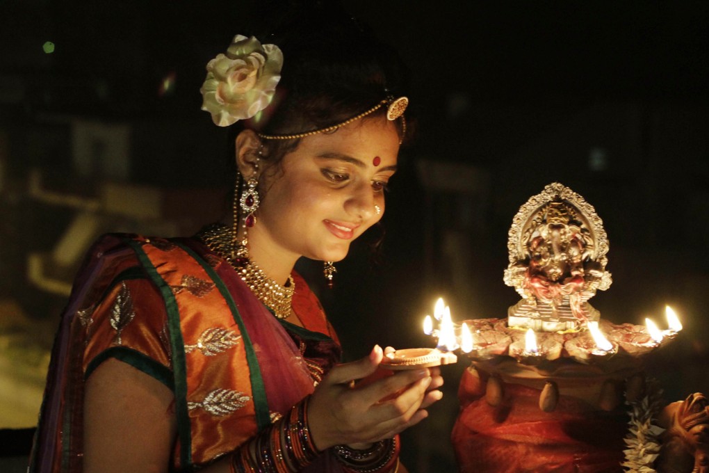 An Indian girl lights an earthen lamp ahead of Diwali, the Hindu festival of light, in Ahmedabad. Photo: AP