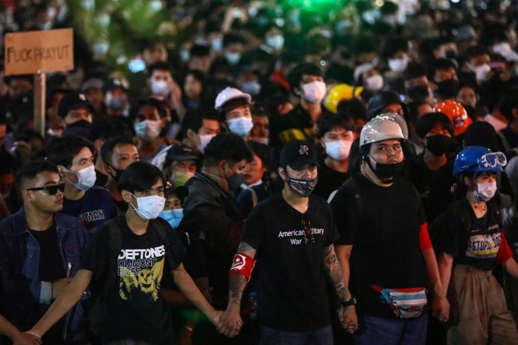 Pro-democracy protesters holds hands as they march during an anti-government demonstration in Bangkok on Sunday. Photo: AFP