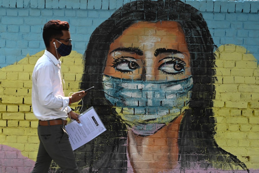 A man walks past a mural in New Delhi depicting a woman wearing a mask on Saturday. Photo: AFP