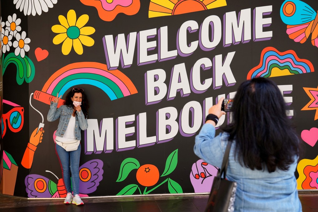 FILE PHOTO: People take photos in front of a 'Welcome Back' sign in Melbourne after coronavirus disease (COVID-19) restrictions were eased for the state of Victoria, Australia, October 28, 2020. REUTERS/Sandra Sanders/File Photo