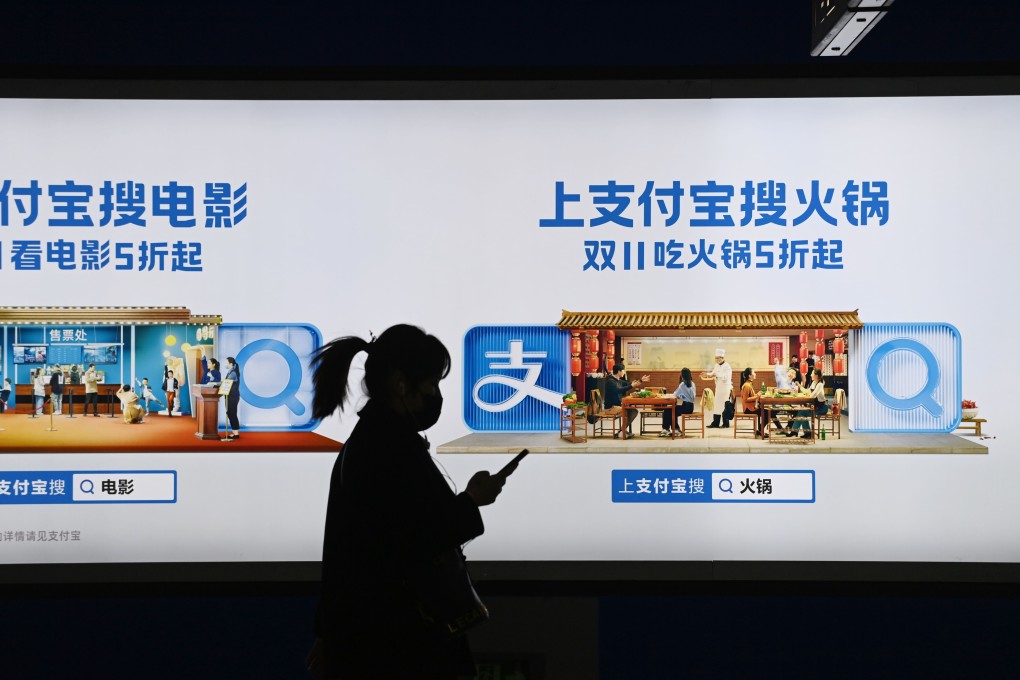 A woman walks past an Alipay advertising hoarding in a subway in Beijing. Photo: AFP