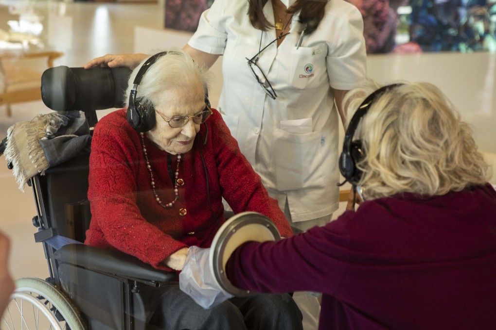 A woman holds the hands of a relative through a plastic film screen and a glass to avoid contracting Covid-19, at a nursing home in Castelfranco Veneto, Italy on Wednesday. Photo: AP