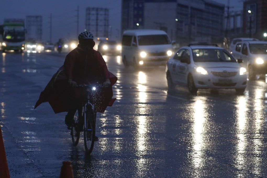 A man in a raincoat rides his bicycle through heavy rain from Typhoon Vamco in Quezon City, Philippines on Wednesday. Photo: AP