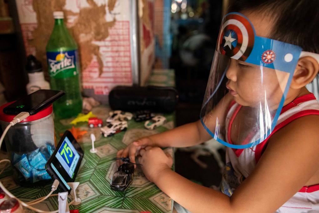 A boy wears a face shield while watching an online learning programme on a smartphone in Manila, Philippines, on August 17. Photo: Reuters