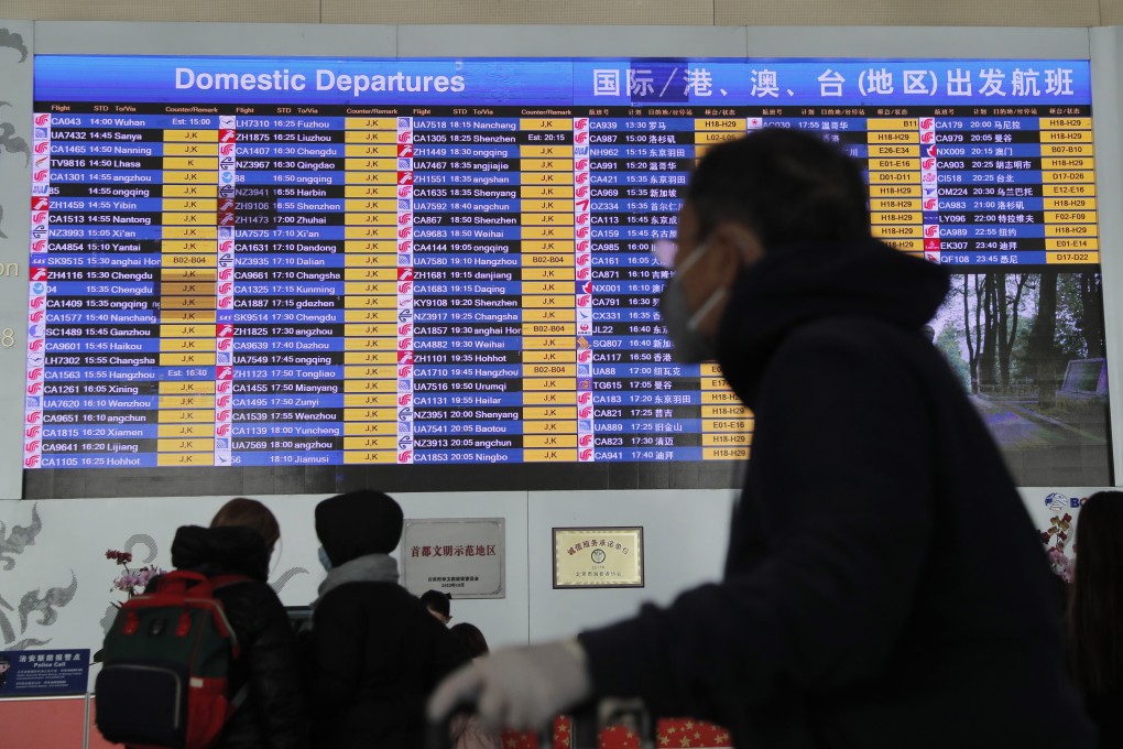epa08165779 A passenger wears a mask passing by a departure information screen at terminal 3 of Beijing Capital International Airport in Beijing, China, 26 January 2020. Chinese official required all travel agencies to suspend the sale of all domestic and overseas group travel products due to coronavirus outbreak. EPA-EFE/WU HONG