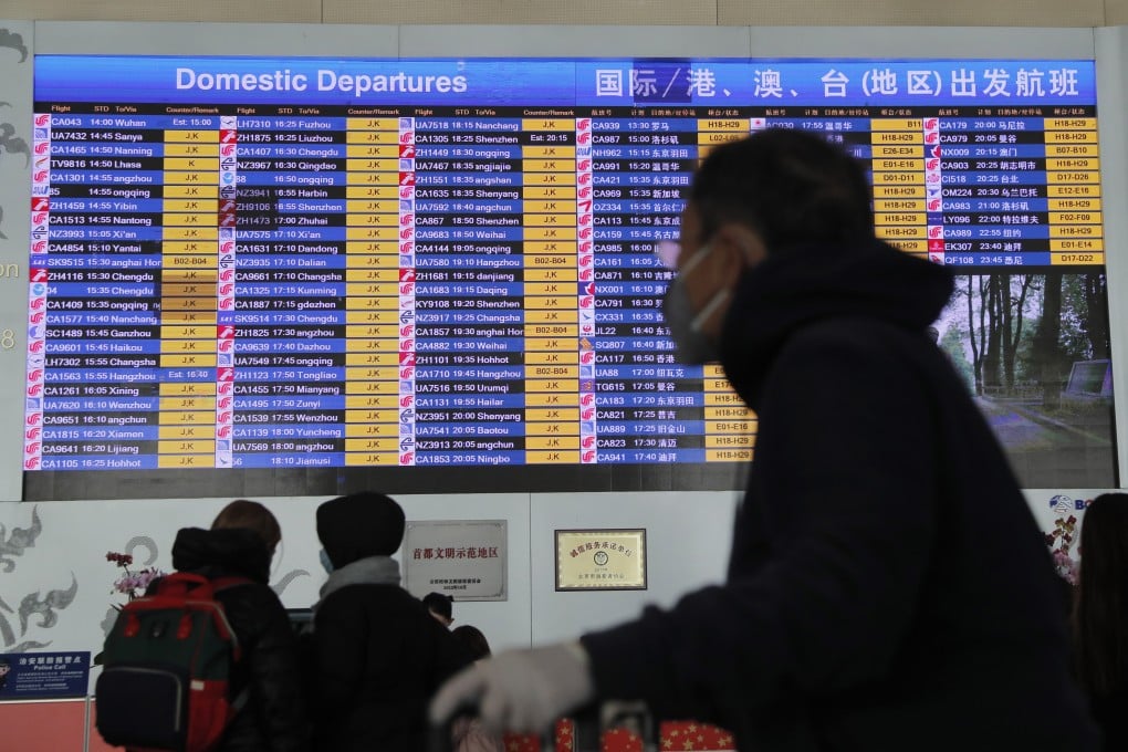 epa08165779 A passenger wears a mask passing by a departure information screen at terminal 3 of Beijing Capital International Airport in Beijing, China, 26 January 2020. Chinese official required all travel agencies to suspend the sale of all domestic and overseas group travel products due to coronavirus outbreak. EPA-EFE/WU HONG