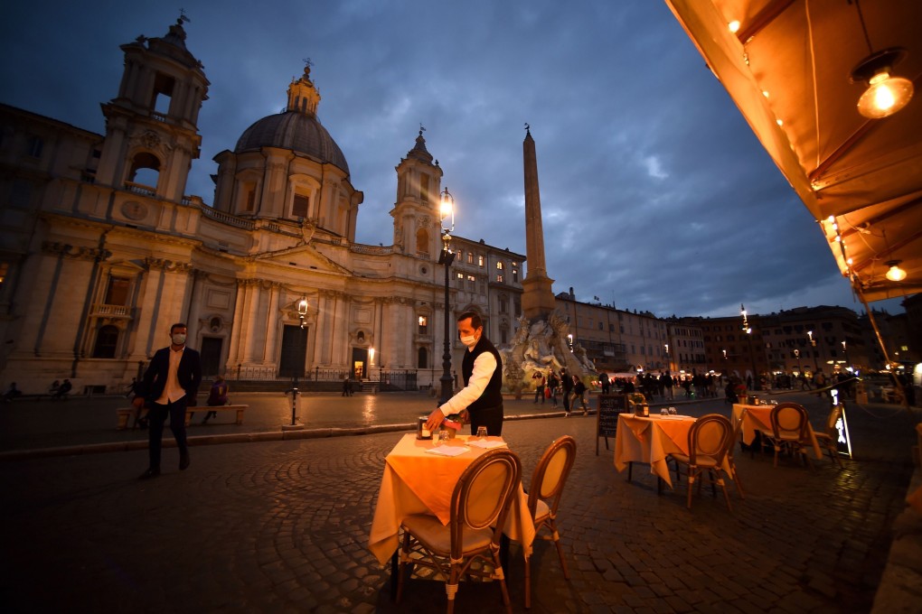An employee tidies a table on an empty terrace at Piazza Navona in Rome on October 23, before a coronavirus curfew was imposed. Photo: TNS