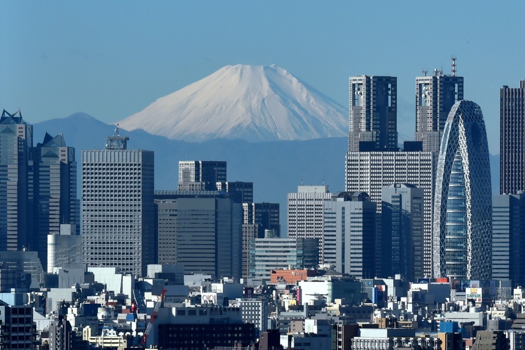 Japan's highest mountain, Mount Fuji, seen in the distance behind the skyline of the Shinjuku area of Tokyo. Photo: AFP