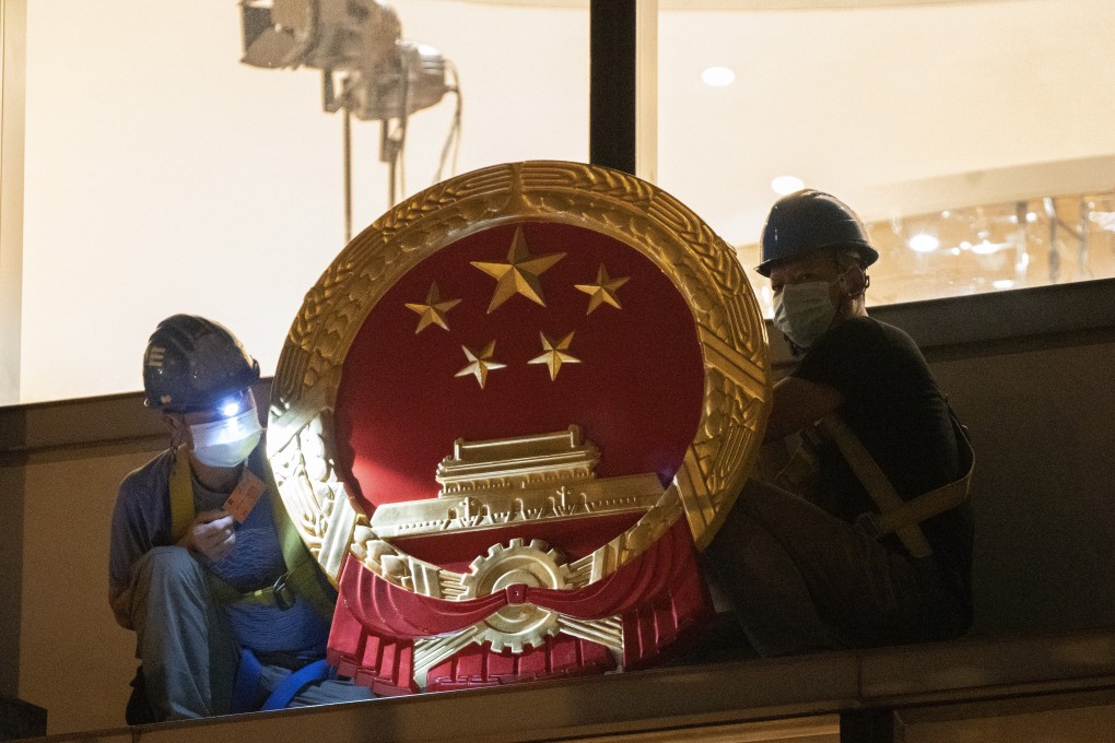 Workers place a national emblem outside the Metropark Hotel in Causeway, as the four-star property became the new temporary headquarters of the Office for Safeguarding National Security, on July 8. Photo: Robert Ng