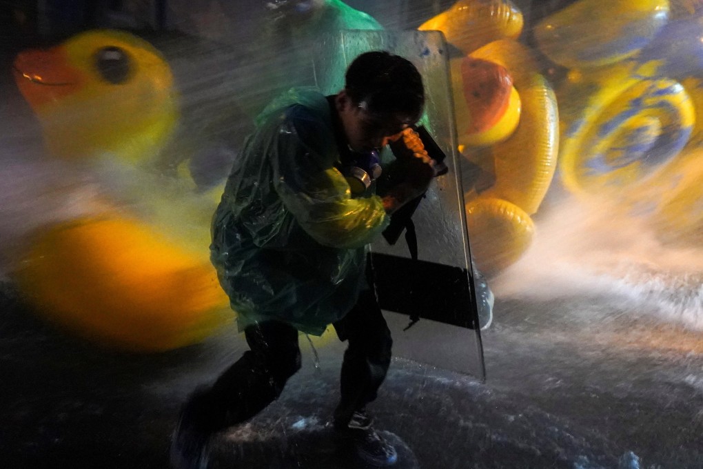 A demonstrator uses a shield as a protection against water cannons, with inflatable rubber ducks in the background, during a pro-democracy protest in Bangkok. Photo: Reuters