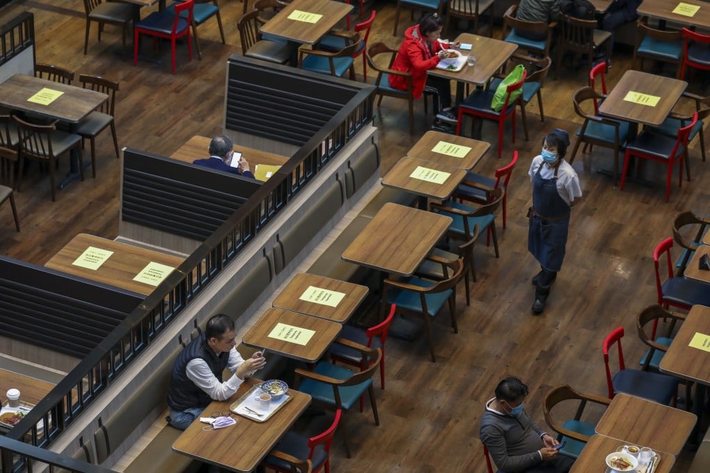 A waitress walks through a restaurant in which tables and chairs have been taped to comply with social distancing regulations in Admiralty, Hong Kong, on March 29. Photo: Nora Tam