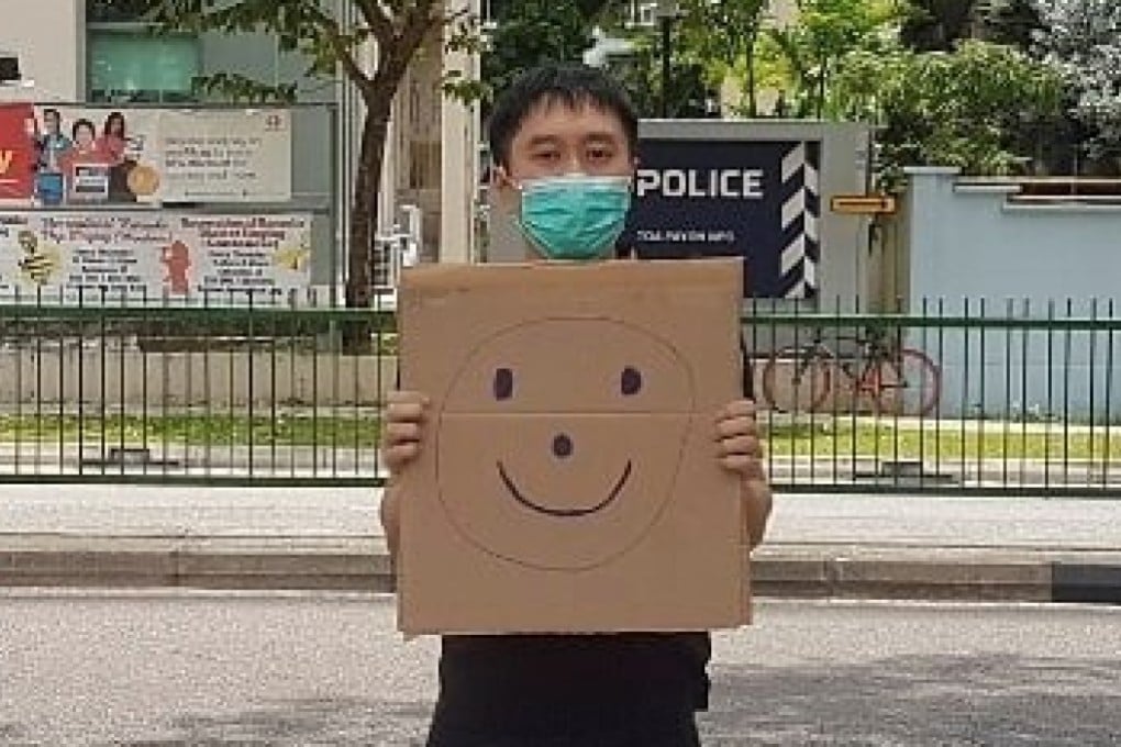 Jolovan Wham holds a cardboard with a drawing of a smiley face in Singapore on March 28, 2020. Photo: Handout via Reuters