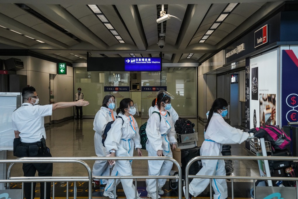 An official gestures travellers in protective gear towards a quarantine area in the arrivals hall of Hong Kong International Airport on July 15. Photo: Bloomberg