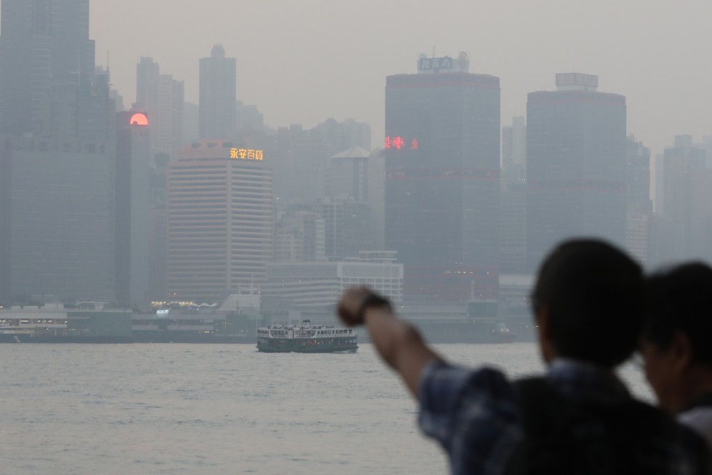 Tourists in Tsim Sha Tsui look across Victoria Harbour on a poor air quality day in November 2018. Photo: Sam Tsang