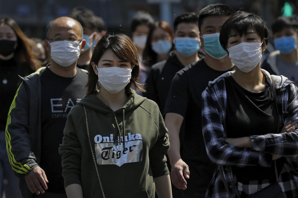 People wearing protective face masks to prevent the spread of the new coronavirus walk across a street in Beijing on Sunday, April 12, 2020. Photo: Andy Wong