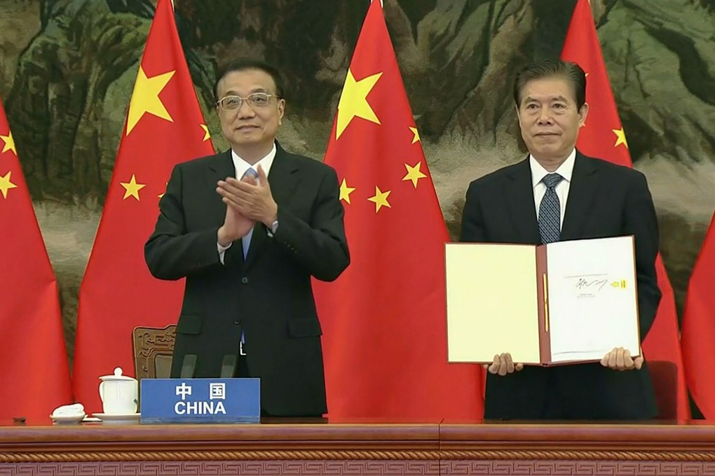 China’s Premier Li Keqiang claps as Chinese Minister of Commerce Zhong Shan holds up the RCEP agreement during the signing ceremony on November 15. Photo: AFP/ Vietnam host broadcaster