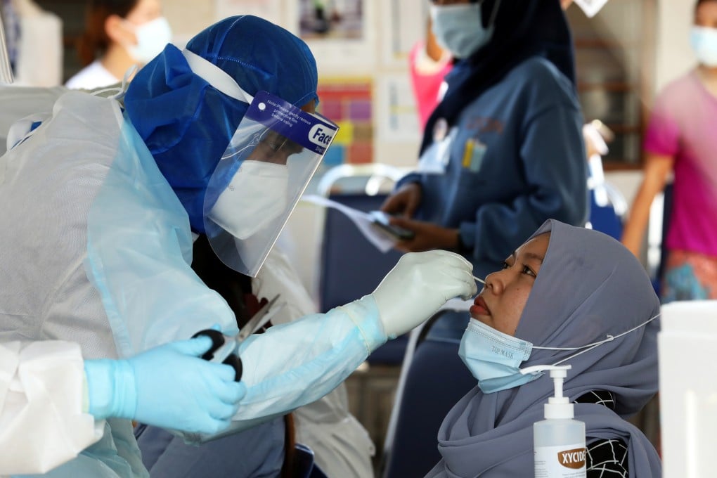 A Malaysian medical worker collects samples from employees at a Top Glove factory in Klang. Photo: Reuters