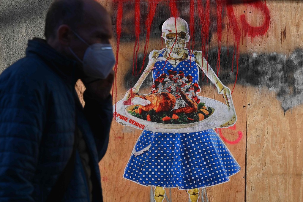 A man walks by street art by @puregenius in New York showing a skeleton holding a tray with a Thanksgiving turkey topped with coronavirus. Photo: AFP