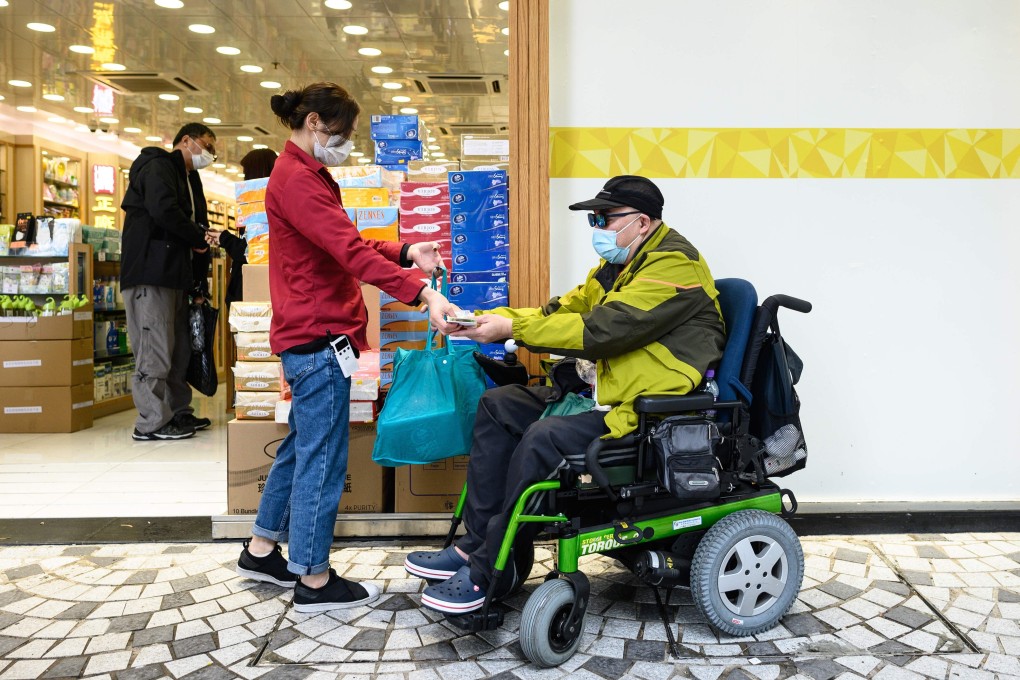 A muscular atrophy patient buys a bag of paper towels from a pharmacy in the Sheung Shui on February 13. Covid-19 has forced many people to grapple with difficulties that those with disabilities routinely face. Photo: AFP