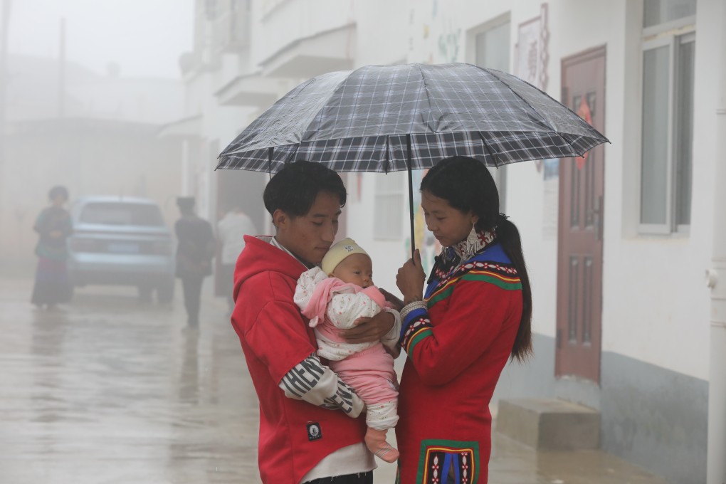 An ethnic Yi couple take care of their child in the rain. Xujiashan villagers moved into their new houses built by the government in 2019. Xujiashan village of Haitang town, Ganluo county, Liangshan prefecture, is one of the 20 extremely poor villages in Ganluo county. Photo: Simon Song