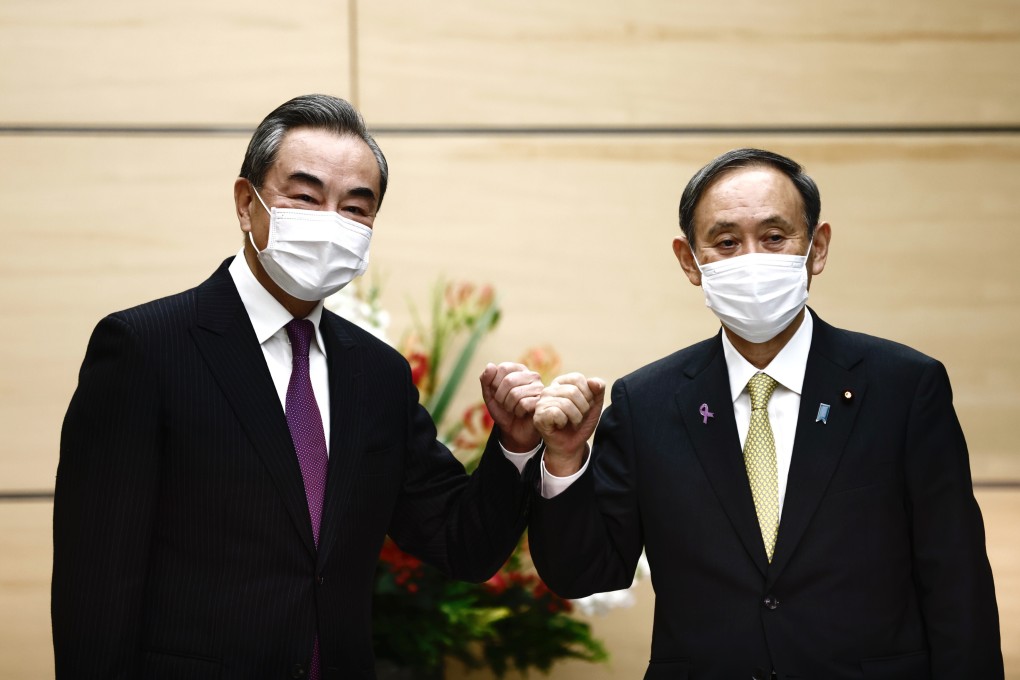 Wang Yi, China's foreign minister, left, bumps fists with Yoshihide Suga, Japan's prime minister, ahead of their meeting in Tokyo, Japan, last week. Photo: Bloomberg