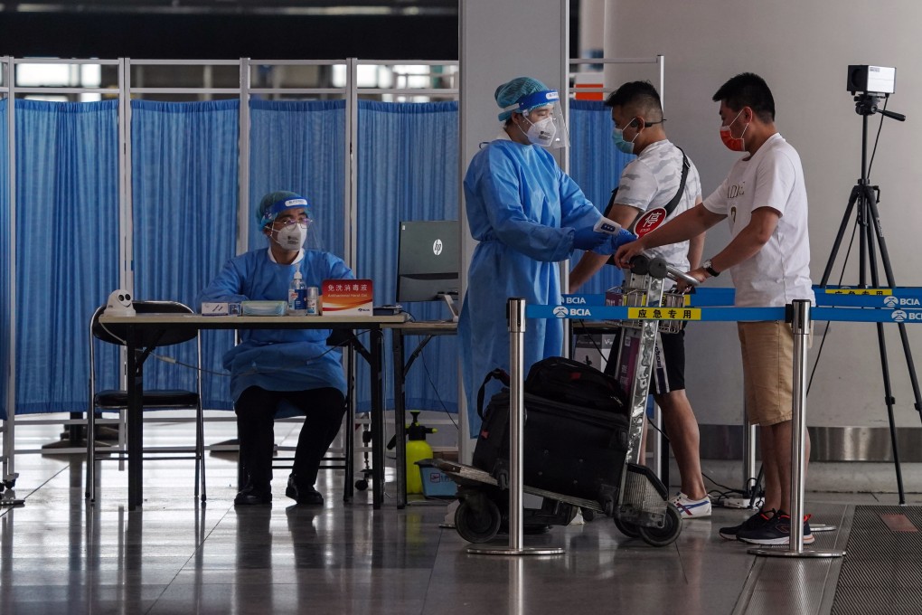 Airport security staff check the temperature of passengers at Beijing Capital International Airport. Photo: EPA-EFE