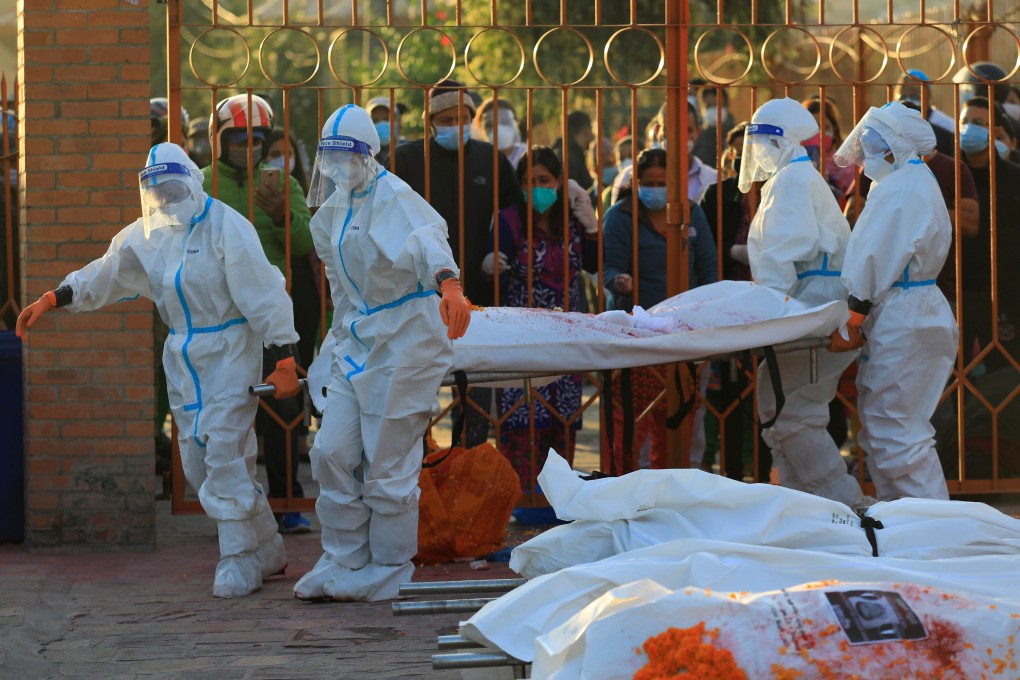 Female soldiers wearing personal protective equipment lift a stretcher with the body of a coronavirus victim as family members mourn at a crematorium in Kathmandu last month. Photo: Reuters