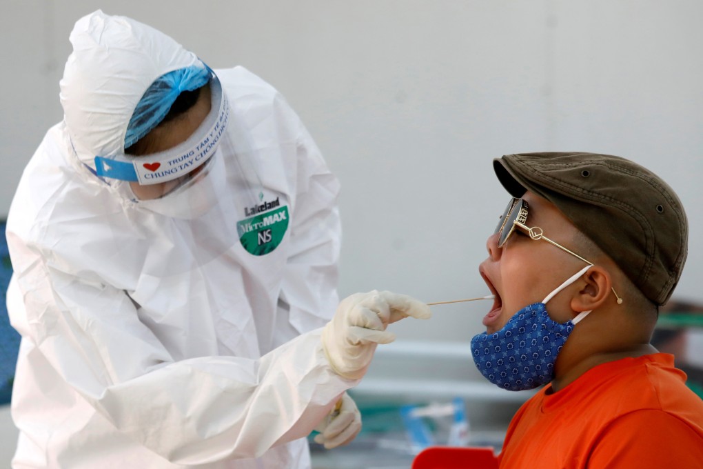 A medical specialist wearing a protective suit collects a swab sample from a traveller who has returned from Da Nang, at a rapid testing centre in Hanoi, Vietnam. Photo: Reuters