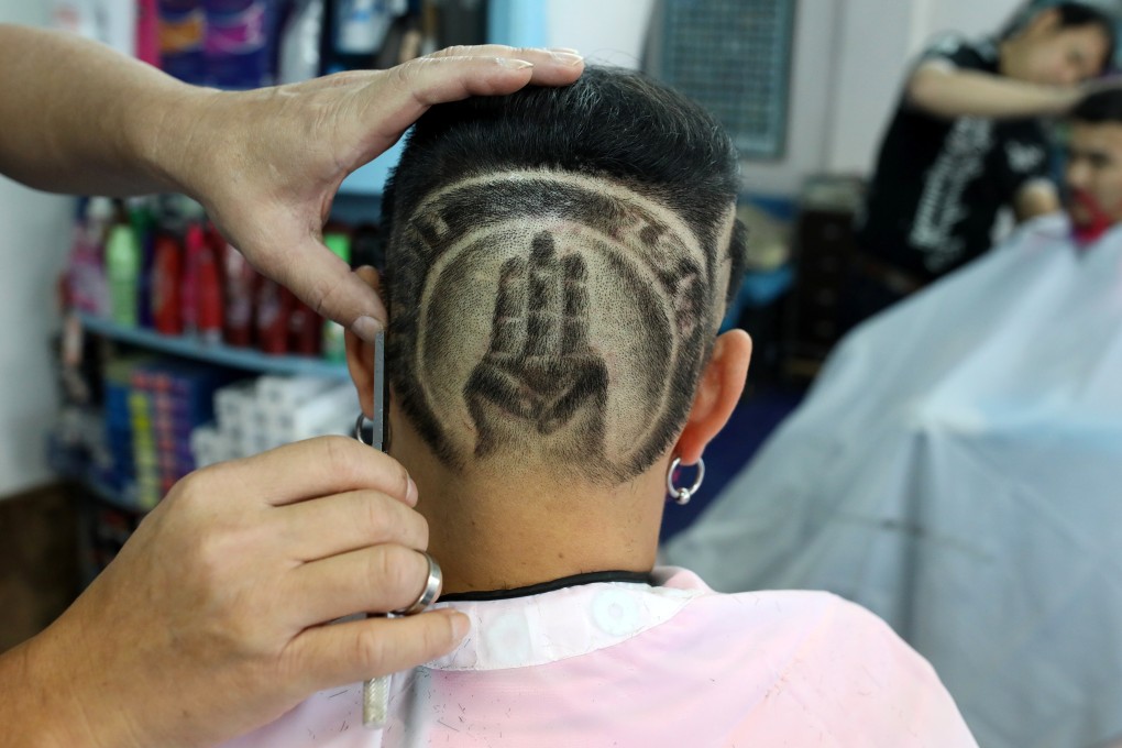 Mitree Chitinunda, a former ultraroyalist who last year got a haircut of King Maha Vajiralongkorn's portrait on the back of his head, has changed his haircut to a symbol of the anti-government protest movement. Photo: Reuters