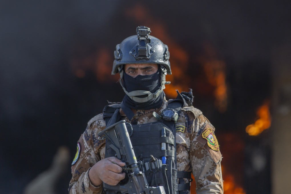 An Iraqi soldier stands guard in front of a fire set by pro-Iranian militiamen and their supporters in the US embassy compound in Baghdad in January. Photo: AP
