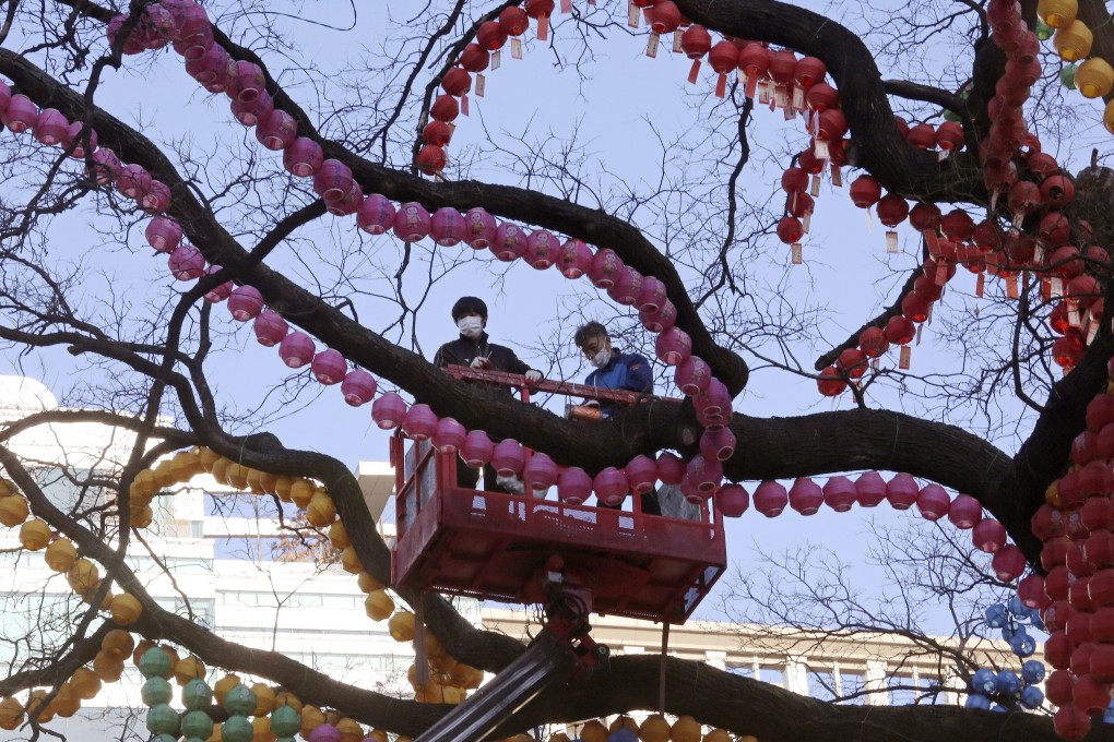 Workers wearing face masks arrange lanterns on a tree to celebrate the upcoming New Year at the Jogyesa Buddhist temple in Seoul, South Korea. Photo: AP
