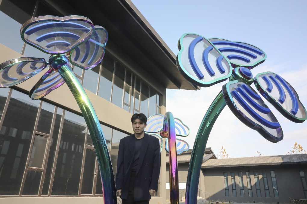 Michael Xufu Huang poses with Wifi-flower Garden (2020), by Meltingwang aka Wang Yuchen, at the X Museum in Beijing. Photo: Simon Song
