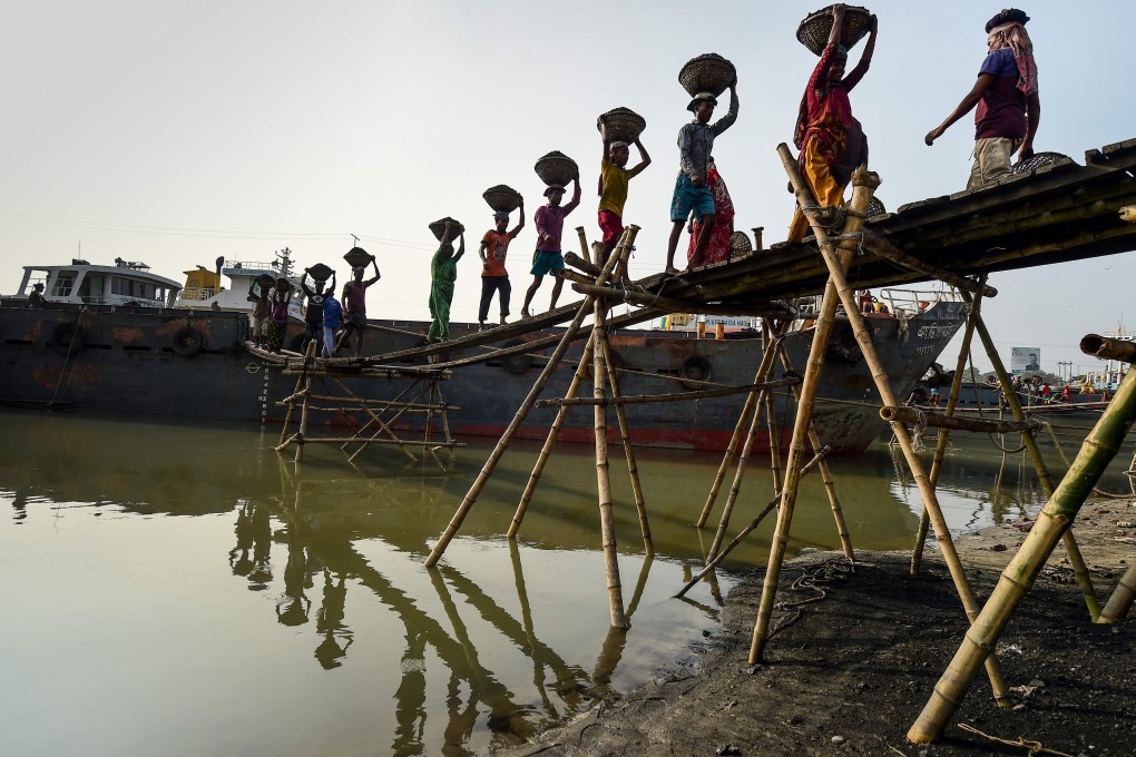 Labourers unload coal from a cargo ship in Gabtoli on the outskirts of Dhaka, Bangladesh, on November 6, 2019. Developing countries such as Bangladesh are reducing their dependence on coal, raising the importance of environmental considerations in infrastructure investment. Photo: AFP