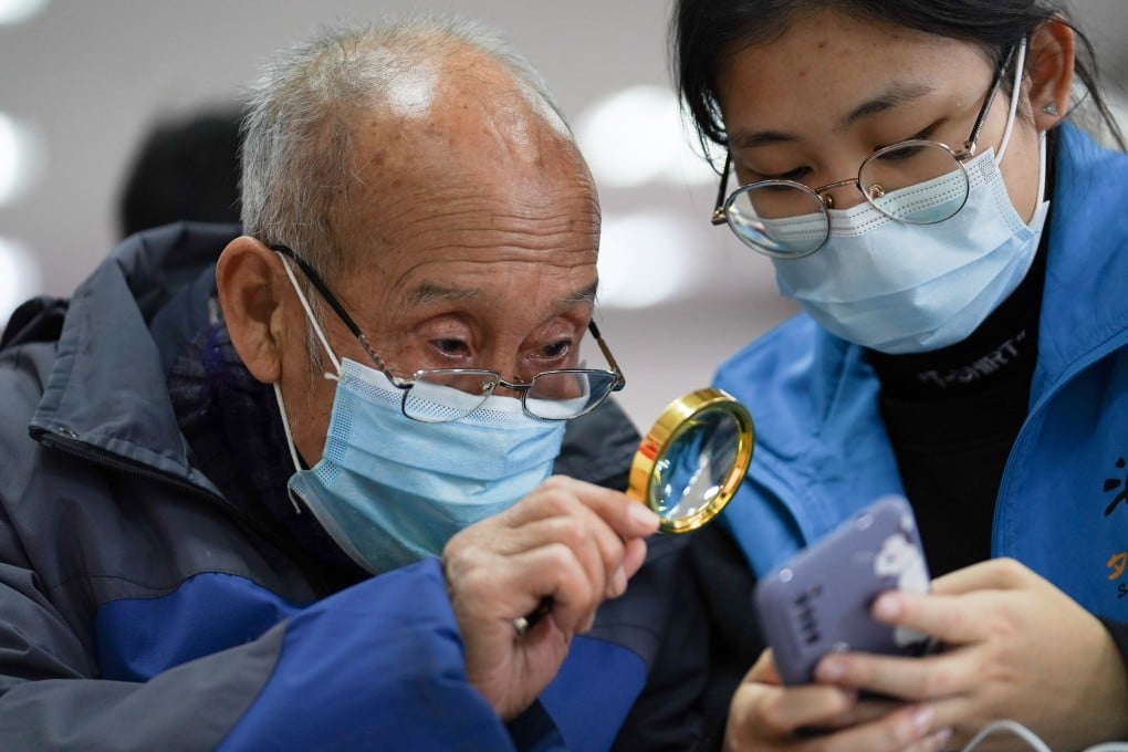 A student volunteer shows an elderly resident how to make a hospital appointment using a smartphone in Beijing earlier this month. Photo: Xinhua